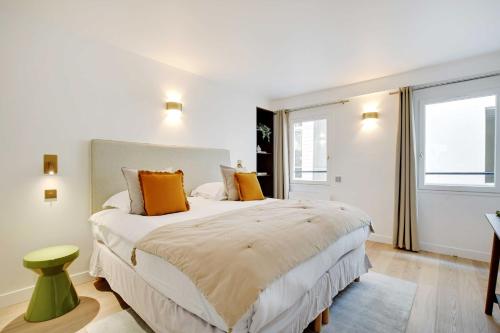 - une chambre blanche avec un grand lit et des oreillers orange dans l'établissement Superb apartment with AC - 1BR-2P - Arts et Métier, à Paris