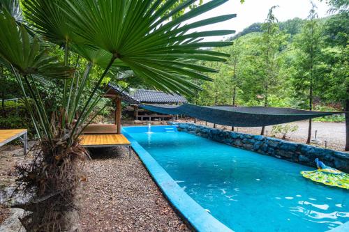 a swimming pool with a hammock in a resort at Gwangyang Sukhee's Hwangto Pension in Gwangyang