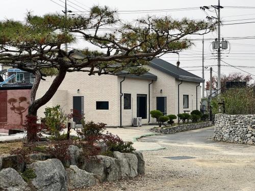 a white building with a tree in front of it at Nonsan Oyeo Poolvilla in Nonsan