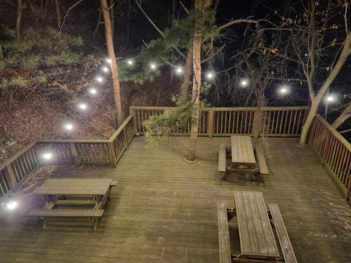 two benches sitting on a wooden deck at night at Goesan Joryeong Pension in Sangch'o