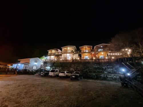 a large house with cars parked in front of it at night at Goesan Joryeong Pension in Sangch'o