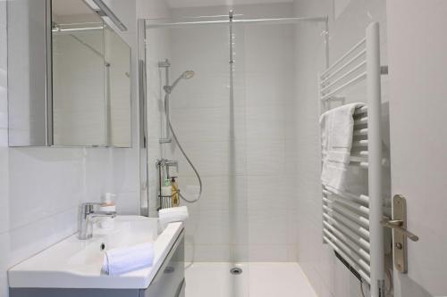 une salle de bain blanche avec un lavabo et une douche dans l'établissement Maison climatisée Gare à 10 min, idéale familles MaisonCarréeConciergerie, à Nîmes