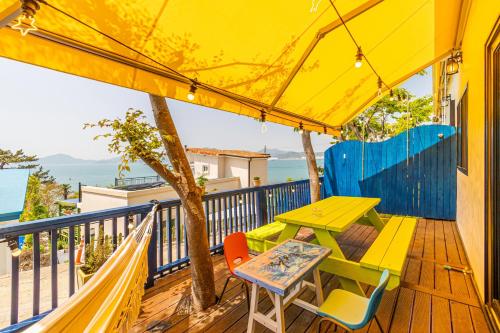 a table and chairs on a deck with a yellow umbrella at Namhae arahil pension in Namhae