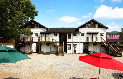 a large white house with two decks and two umbrellas at Cheongju Okhwadaestory Pension in Cheongju