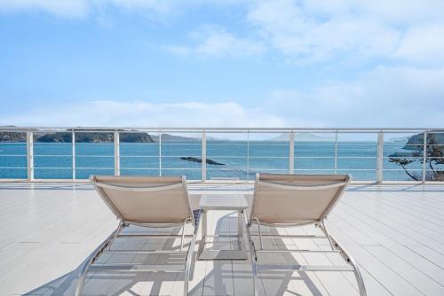 two chairs and a table on a balcony with the ocean at Namhae Yeogi Namhae in Namhae
