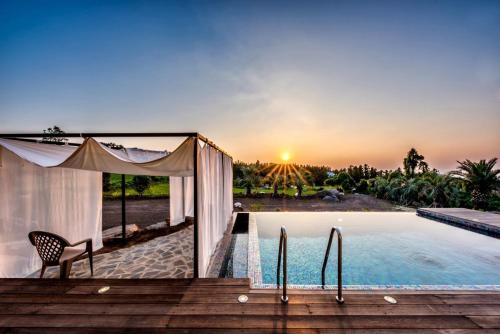a villa with a swimming pool with a table and a chair at Jeju Mia Private Pool Villa large outdoor warm pool in Jeju