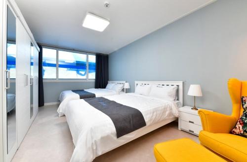 a bedroom with two beds and a yellow chair at Airini Pension in Damyang