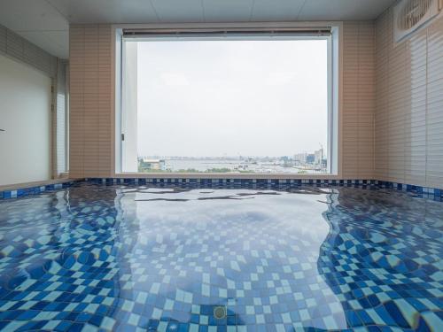 a swimming pool with blue tiles in a room with a large window at Pohang Pool Villa Yeongil in Pohang