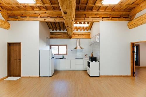 a large kitchen with white appliances and wooden ceilings at Iksan Mureungdowon in Iksan