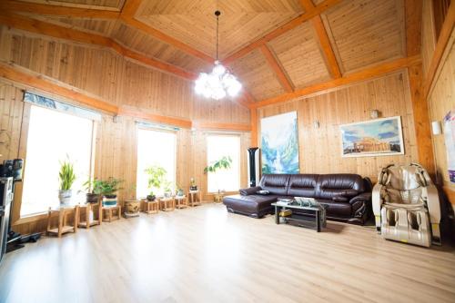 - un salon avec un canapé en cuir dans une chambre dotée de murs en bois dans l'établissement Jeju Woongine Pension, à Jeju