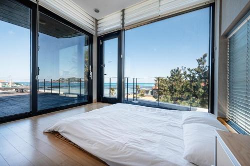 - une chambre avec de grandes fenêtres et un grand lit dans l'établissement Equinox de Geumneung, à Jeju