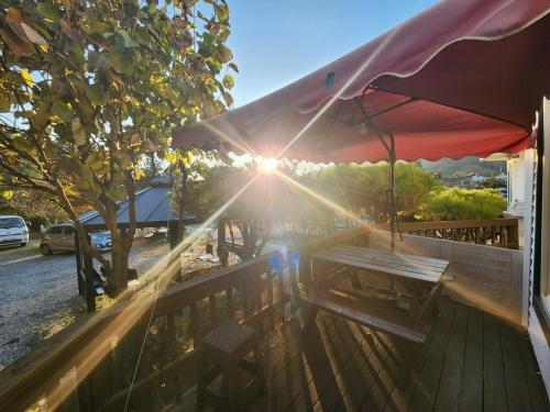 a wooden deck with a picnic table and a red umbrella at Anmyeondo Titicaca Pension in Taean