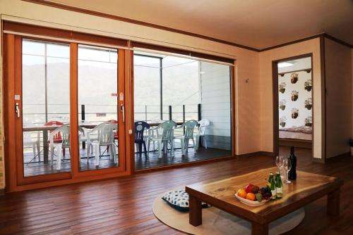 a living room with a table and a balcony at Sancheong Jirisan Noul Pension in Sancheong