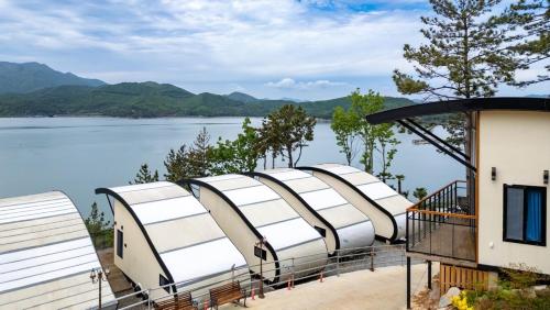 a row of white tents on the edge of a lake at Goheung Tuttiamo Pension in Goheung