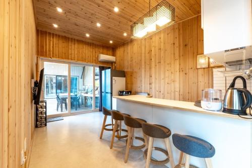 a kitchen with wooden walls and a counter with chairs at Goheung Tuttiamo Pension in Goheung