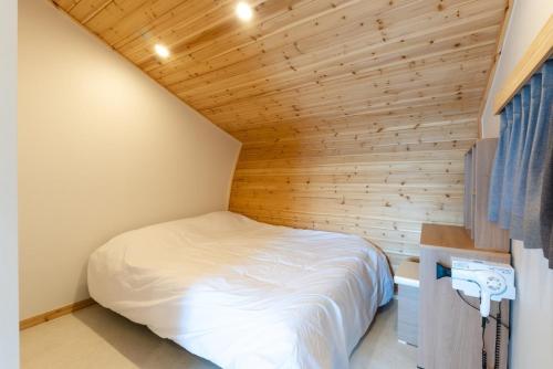 a small bedroom with a bed in a wooden wall at Goheung Tuttiamo Pension in Goheung