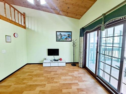 a living room with a television and a large window at Pine Fragrance Green Pension Taean in Taean