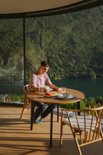 a man sitting at a table on a deck at Sogndal Fjordpanorama- The Panorama View in Kaupanger