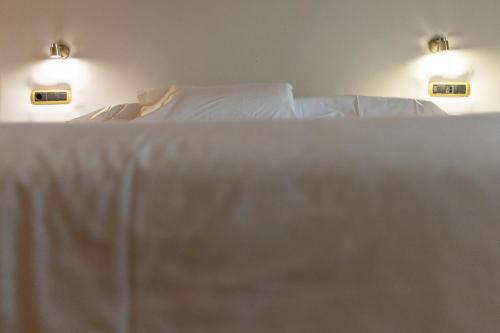 a bedroom with a bed with white sheets and two lights at Hotel Alfonso I in Tui