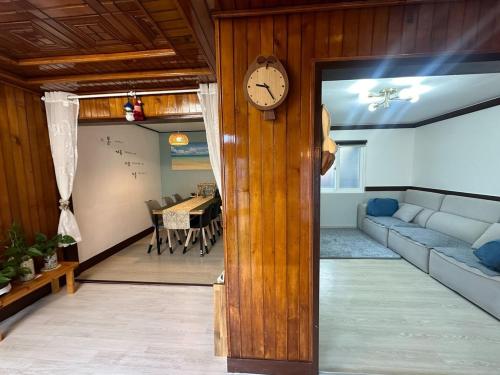 a living room with a clock on a wooden wall at Namhae Audrey House in Namhae