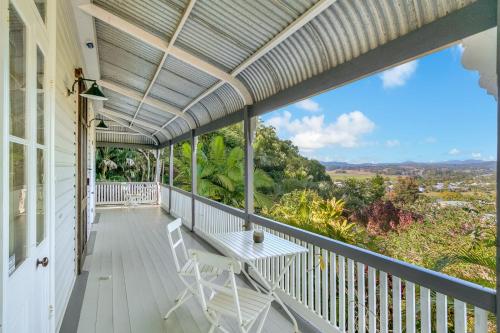 a porch with a white bench and chairs on it at Glenelg Residence in Murwillumbah