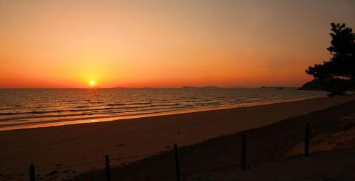 a sunset on the beach with the sun setting at Taean Anmyeondo Pension Marimo in Taean
