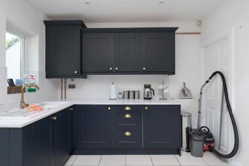 a kitchen with dark blue cabinets and a sink at Spacious & Charming 2BR - Perfect Stay in Northampton
