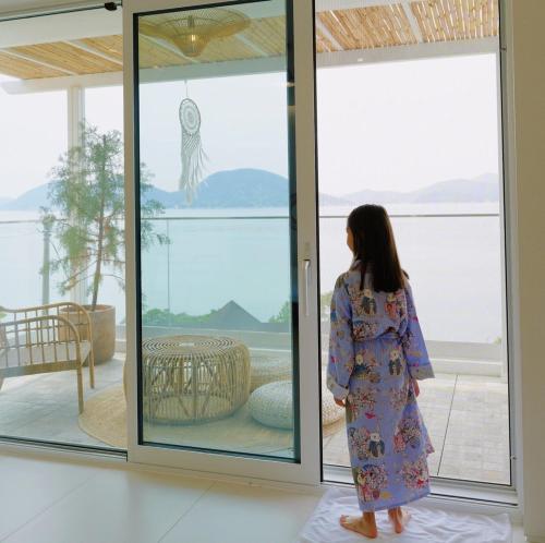 a young girl standing in front of a sliding glass door at On the Sunset Mansion in Geoje 
