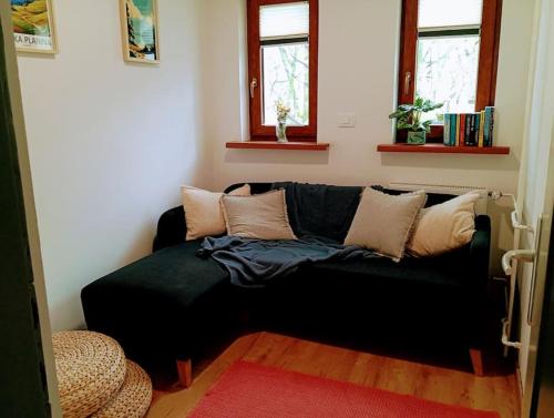 a black couch in a living room with two windows at Apartma Discovering Slovenia in Luče