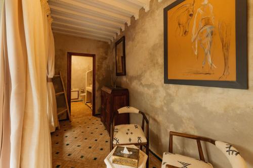 a hallway with chairs and a painting on the wall at Riad Senja in Marrakech