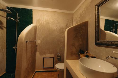 a bathroom with a sink and a toilet and a mirror at Riad Senja in Marrakech