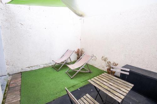 deux chaises et un banc sur une terrasse avec de l'herbe verte dans l'établissement Le cocon authentique, à Tours