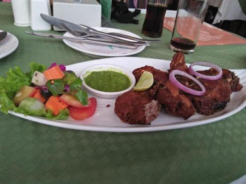 a plate of food with meat and vegetables on a table at Hotel Chhimeki in Kathmandu