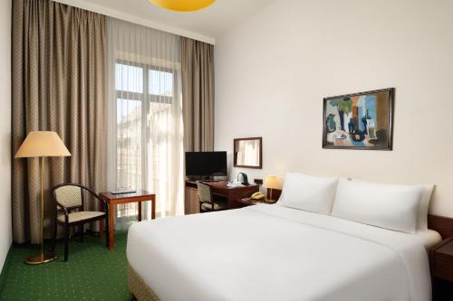a hotel room with a large white bed and a desk at Danubius Hotel Hungaria City Center in Budapest