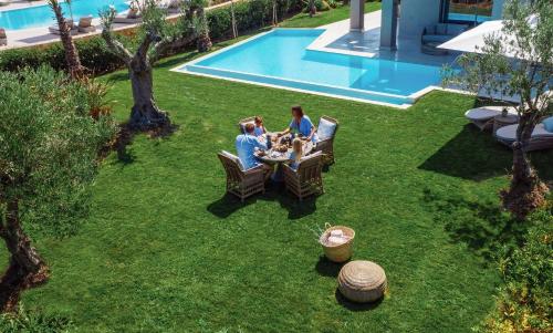 a group of people sitting at a table near a pool at Porto Sani in Sani Beach