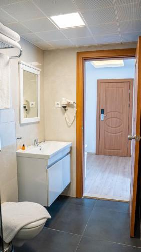 a bathroom with a sink and a toilet and a door at Honeymoon Beach Otel in Marmaris