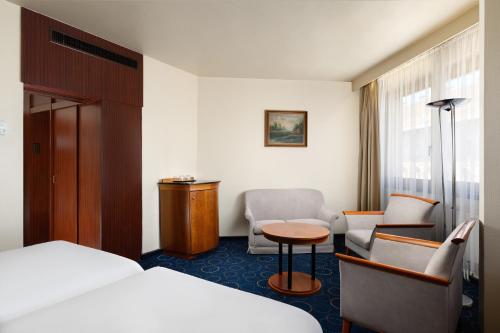 a hotel room with a bed and a table and chairs at Danubius Hotel Hungaria City Center in Budapest
