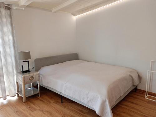 a white bedroom with a bed and a night stand at Apartament Olchowa Prestige 3 in Ustroń
