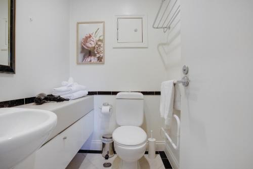 Un baño blanco con inodoro y lavabo. en City Hideaway 1 BR Apt with Pool and Gym, en Auckland