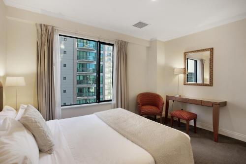 Un dormitorio con una cama y un escritorio y una ventana. en City Hideaway 1 BR Apt with Pool and Gym, en Auckland