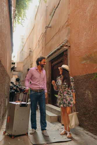 a man and a woman standing on a street with a suitcase at Riad Senja in Marrakech