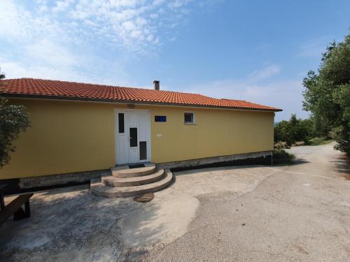 a small yellow house with a white door and stairs at Beachfront House Nella with full privacy in Jasenice