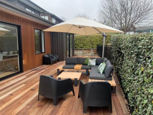 a patio with couches and an umbrella on a deck at Lake Living That Wanaka Tree in Wanaka
