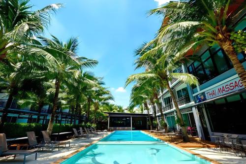 a swimming pool with chairs and palm trees in front of a building at Aranta Suvarnabhumi in Lat Krabang