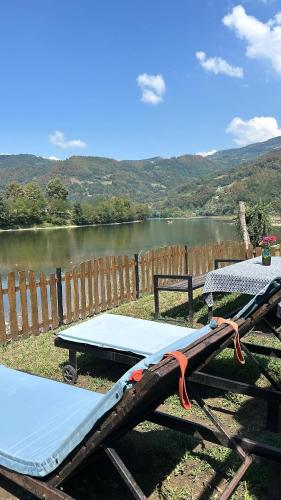 a picnic table next to a lake next to a fence at Vukova Brvnara in Drlače