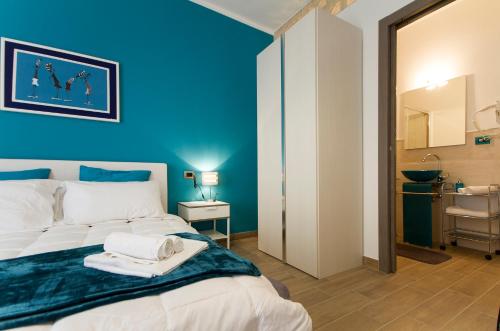 a bedroom with blue walls and a bed with towels on it at Antale in Alghero