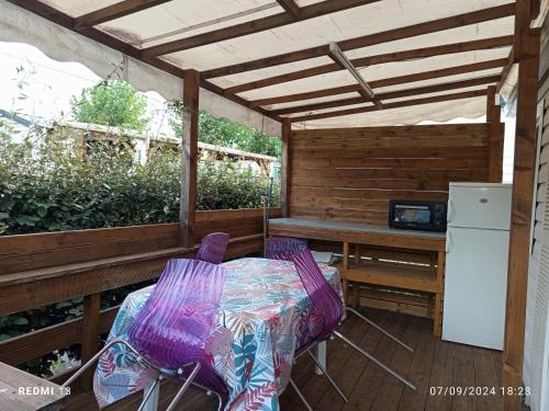 a patio with a table and chairs and a refrigerator at vacances familiales dans camping avec piscine in Fréjus