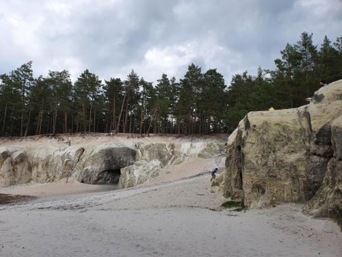 a group of people walking on a beach next to rocks at ****FH Blauvogel 60 Harz in Hasselfelde