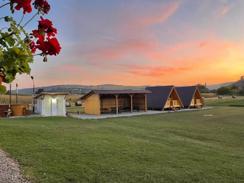 a group of tents in a field with a sunset at La Fermă in Şeíca Mare