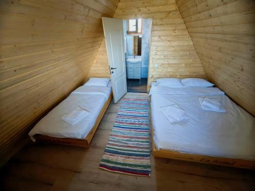 two twin beds in a wooden room with a door at La Fermă in Şeíca Mare